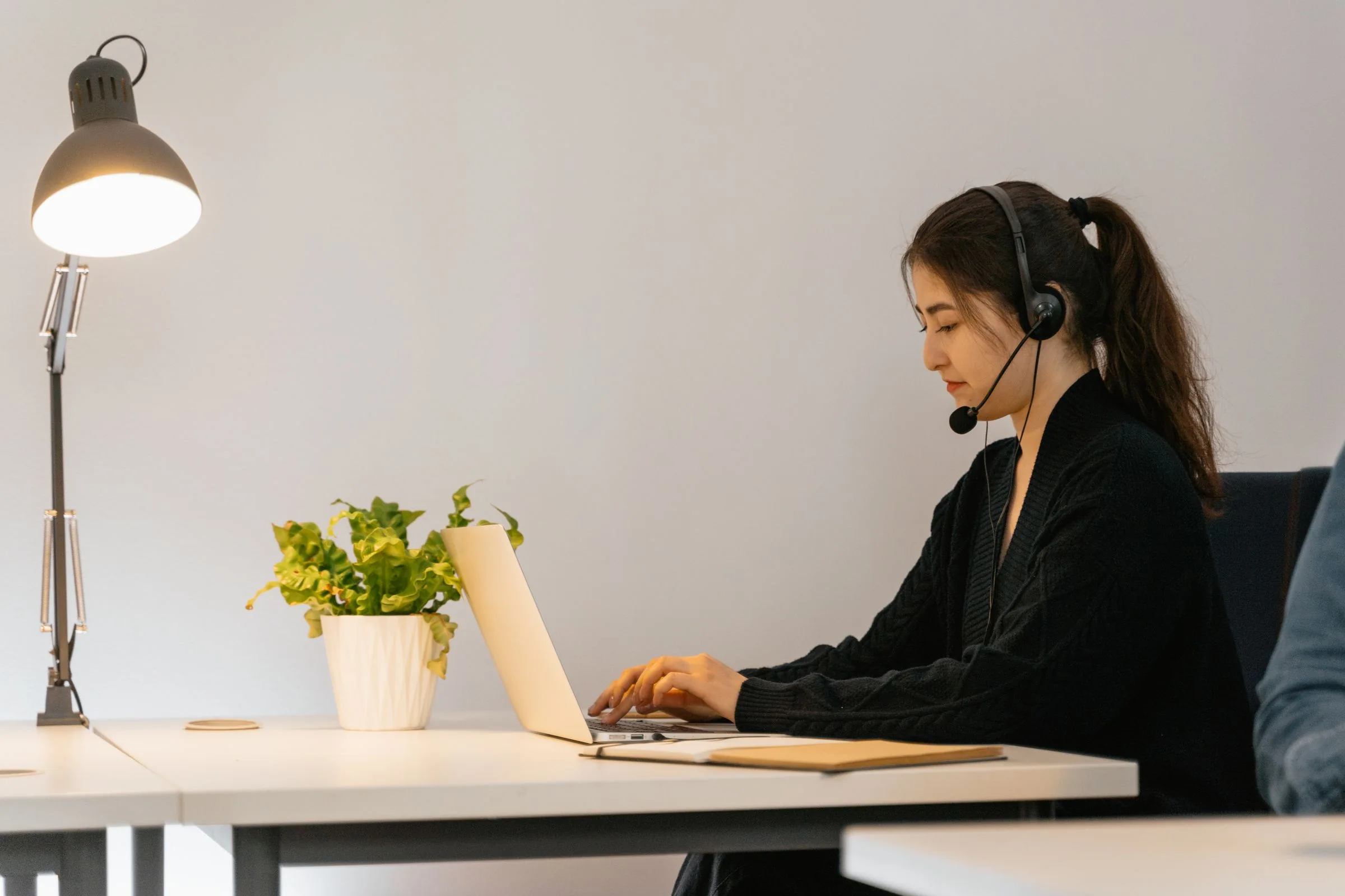A woman wearing a headset while working at a laptop