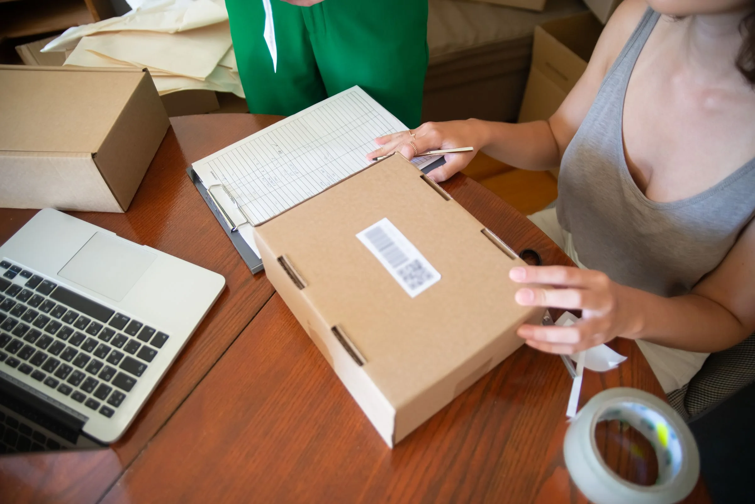 Two people preparing online orders beside a laptop