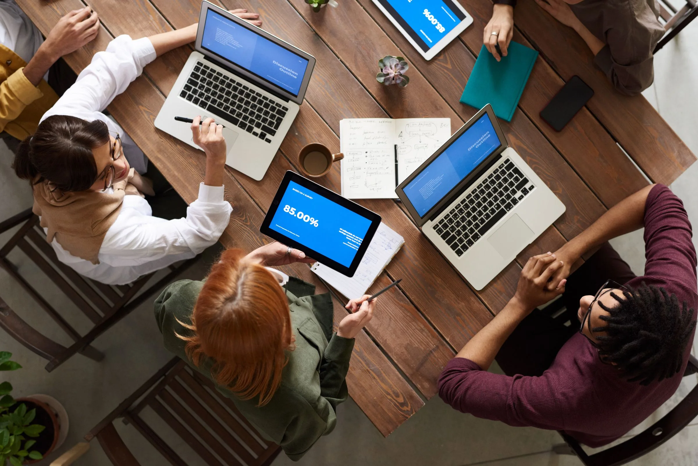 Overhead view of colleagues working together around laptops and notebooks