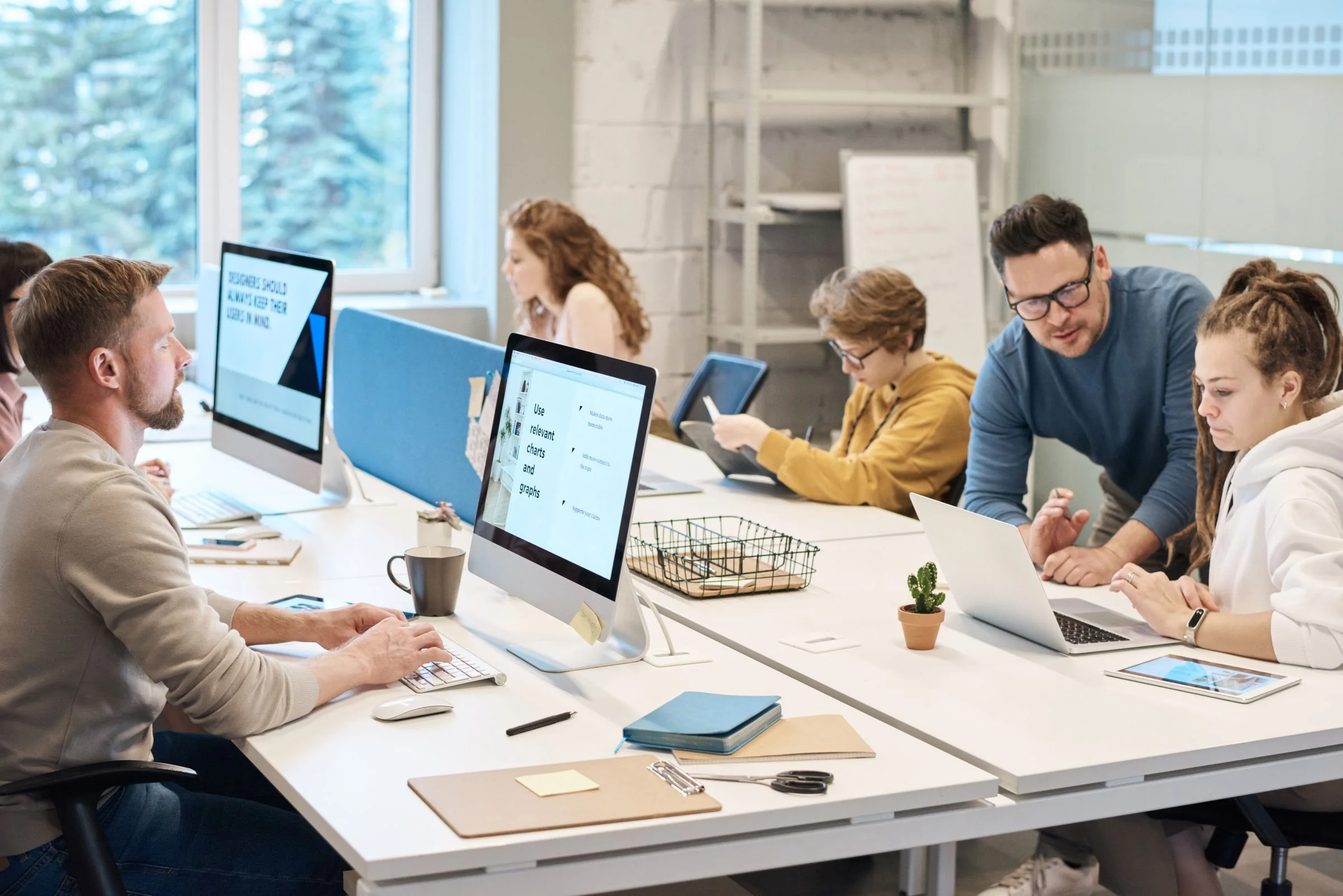 Colleagues collaborating at computers in a bright open office